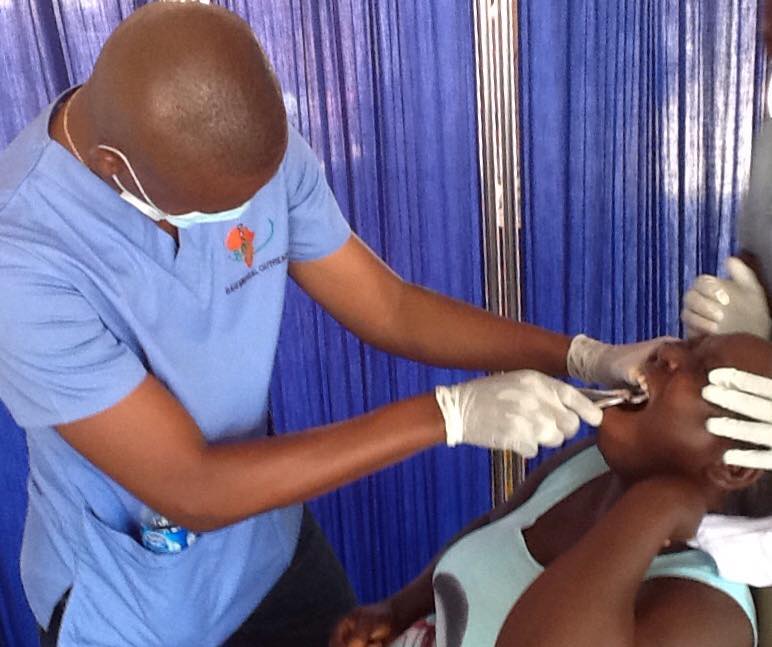 Volunteer dental surgeon carrying out tooth extraction on a patient